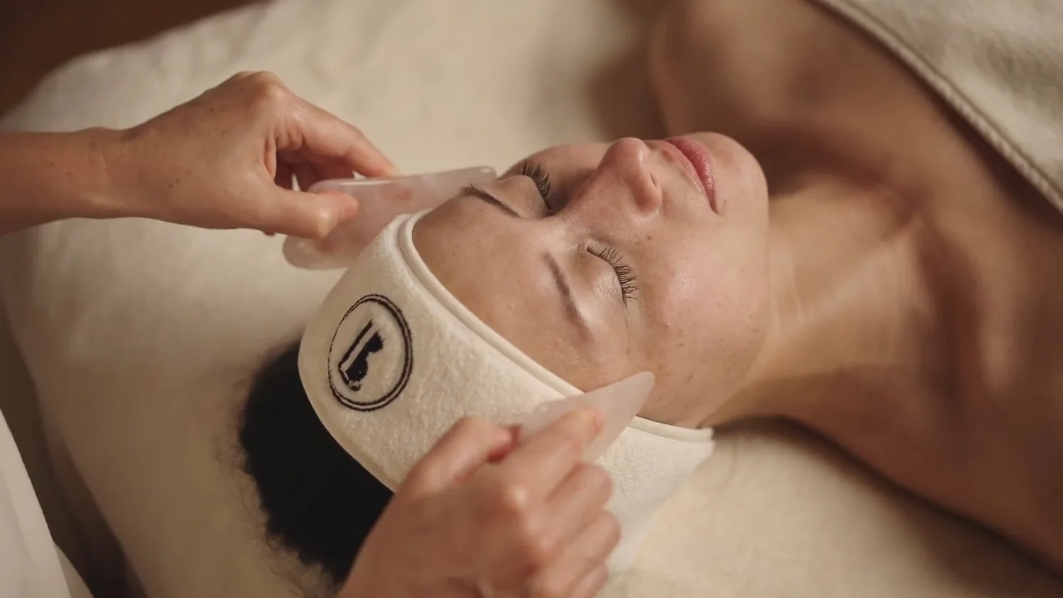 Massage facialiste au Gua Sha en quartz pendant le soin du visage signature à Hossegor