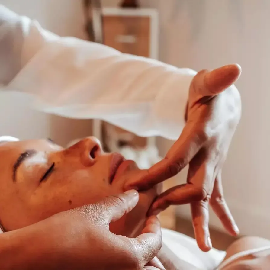 Mains expertes de la facialiste pendant un massage du visage anti-âge